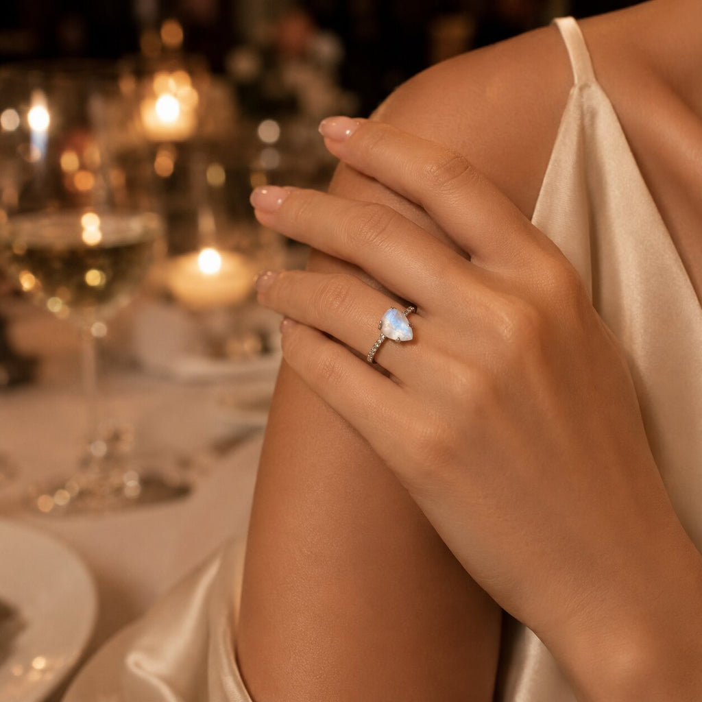Avelune moonstone ring worn on hand with an elegant satin outfit and warm candlelit background