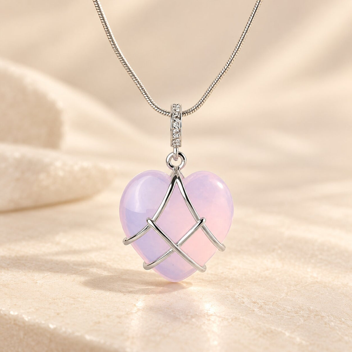 Caelisse Moonstone Heart Necklace with a translucent pastel pink heart gemstone, silver wire wrapping and detailed silver pendant bail on a fine snake chain.