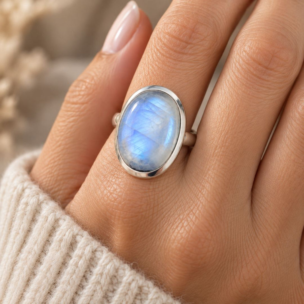 Luna Moonstone Ring worn on a woman's hand with an oval blue-flashing moonstone